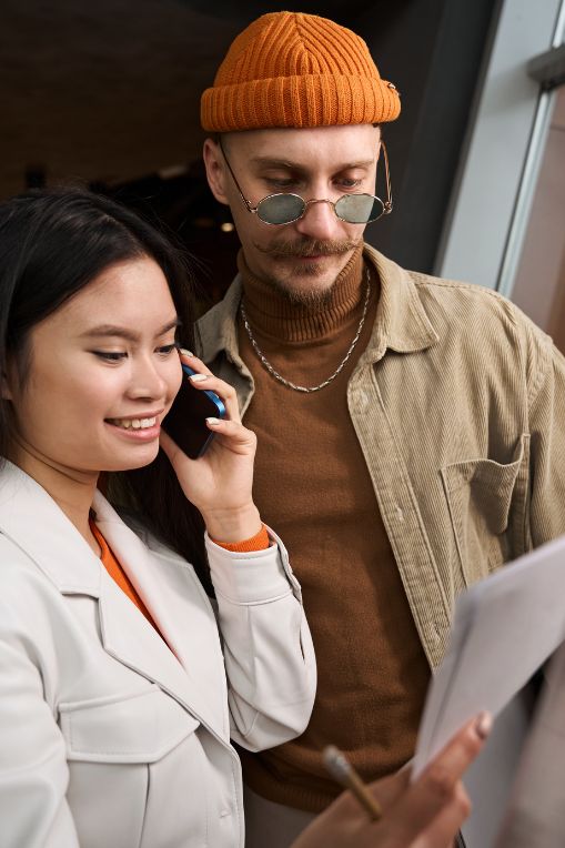 Young professionals reviewing a document together, with one person on a phone call — teamwork in a modern business setting.