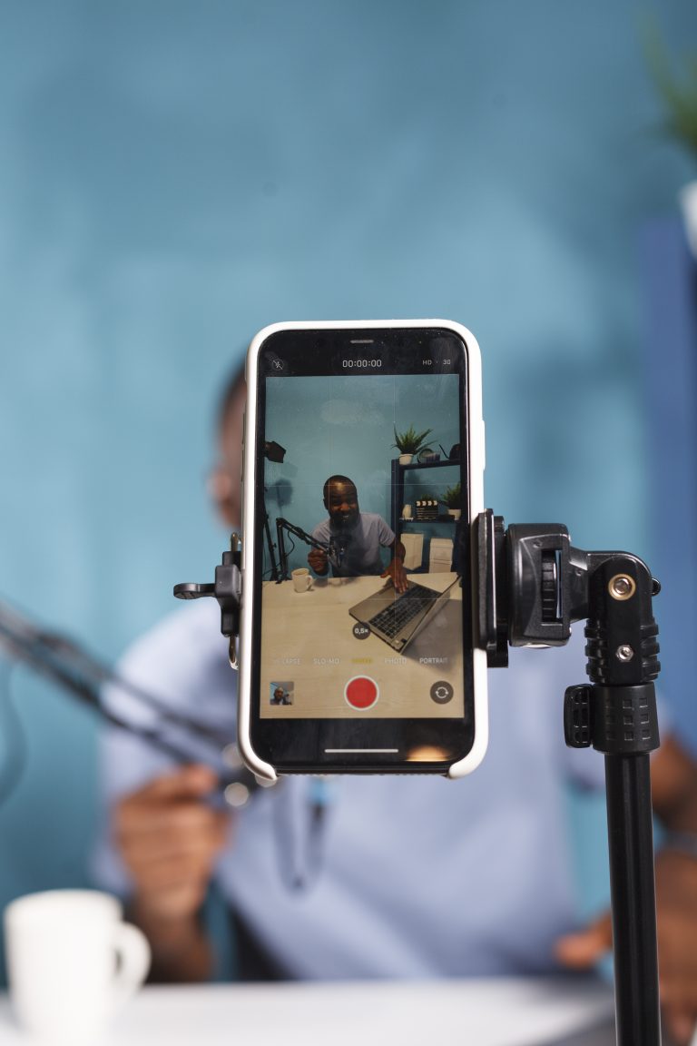 Content creator recording a video at a desk using a smartphone and microphone, illustrating a human-first marketing approach focused on authenticity and connection.